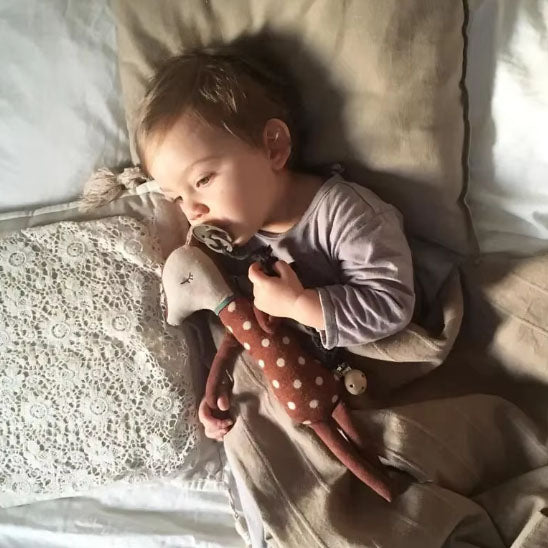 bebe qui sert son doudou bambi