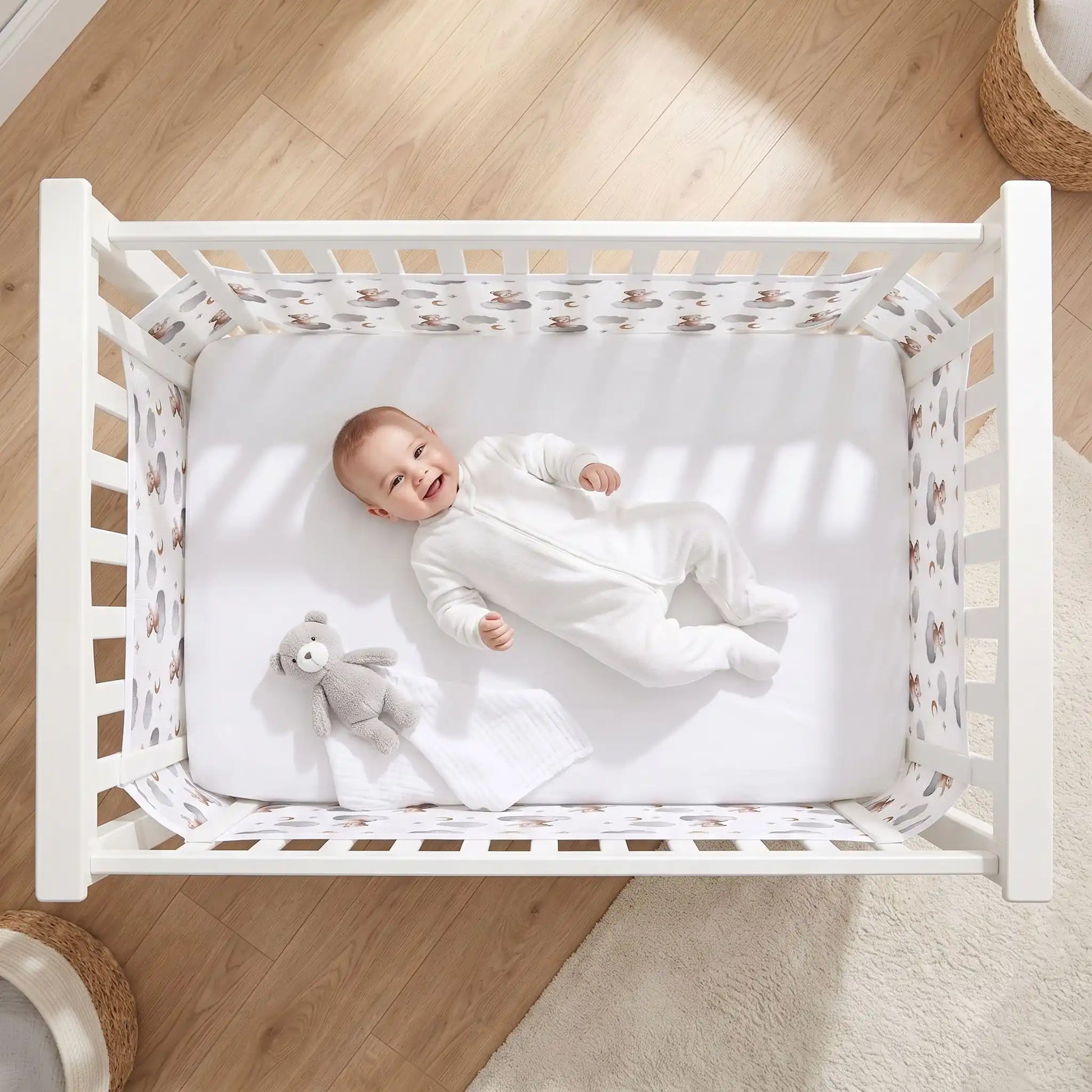 vue aérienne d'un bébé qui sourit dans son lit couché sur le dos dans son lit à barreaux avec un tour de lit bébé filet anti étouffement ourson