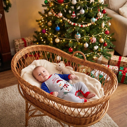 bébé couché dans un panier en osier habillé d'une barboteuse de noël bonhomme de neige avec un sapin de noël derrière