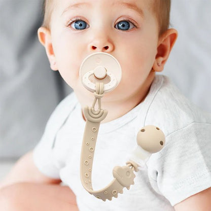 Bébé portant une attache tétine dinosaure longue traîne en silicone alimentaire beige, cadeau de naissance idéal