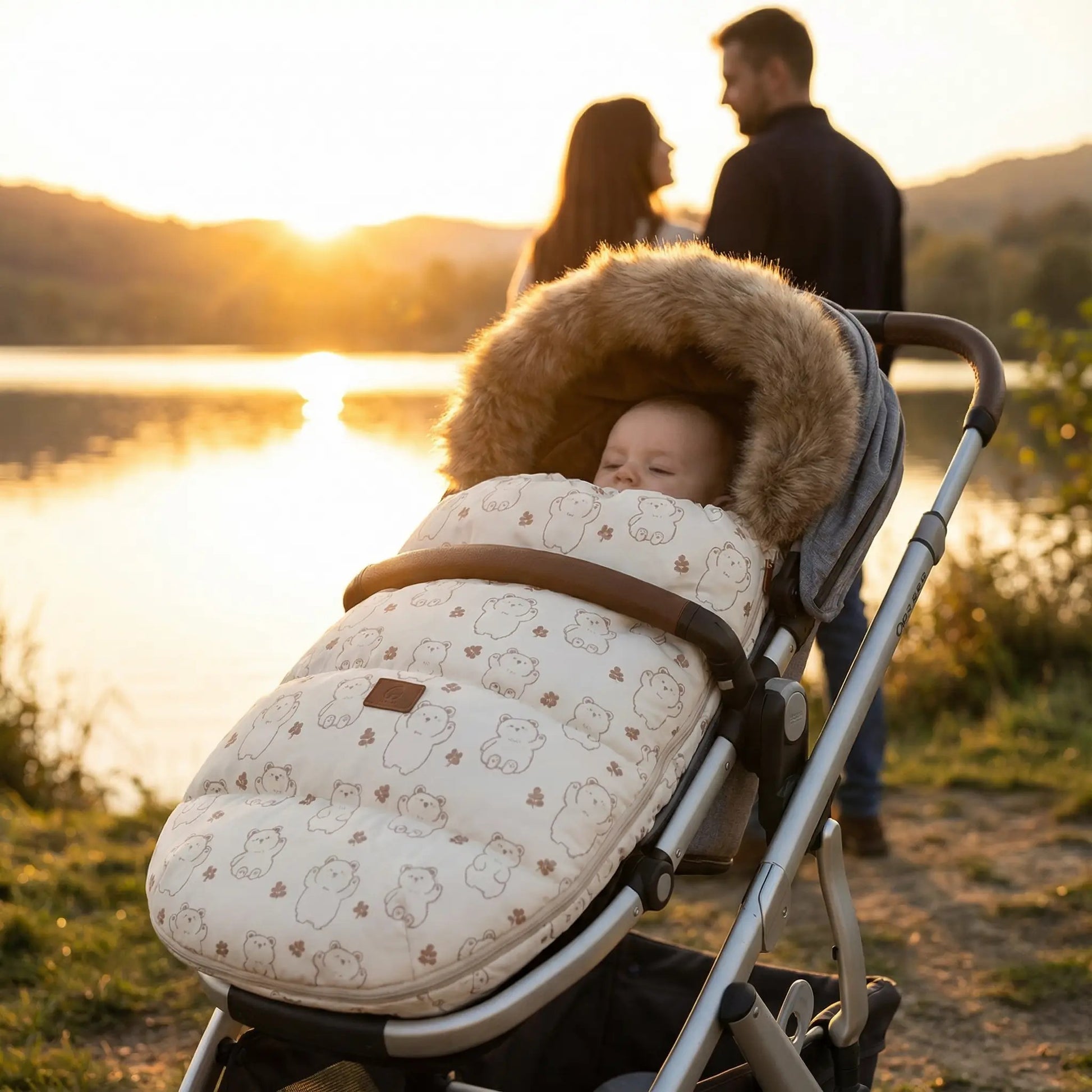 Bébé bien protégé du froid dans sa chancelière universelle avec capuche en fourrure lors d'une balade en poussette en nature au coucher du soleil.