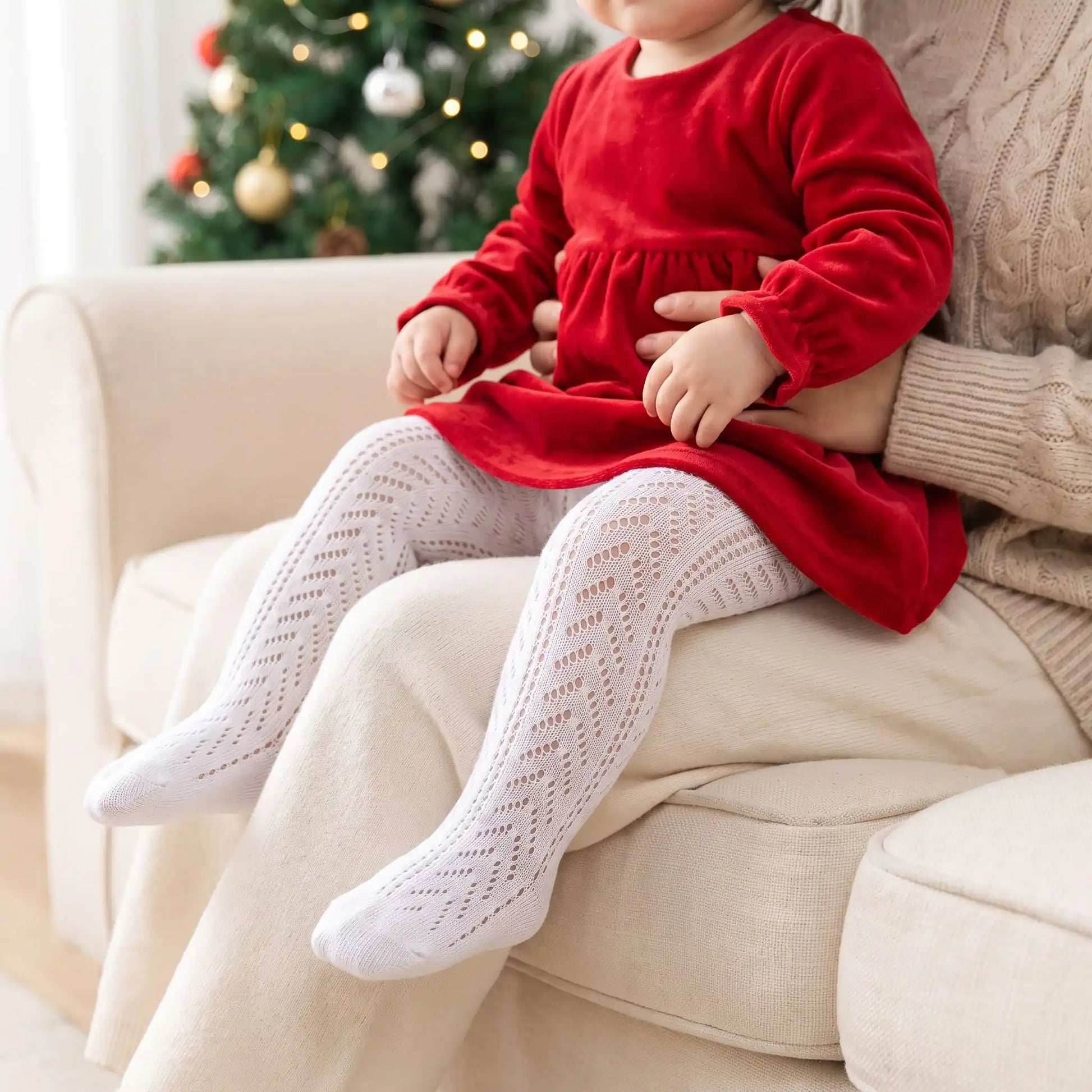 bébé en robe rouge sur les genoux de sa maman avec des collants bébé blanc en coton doux en résille
