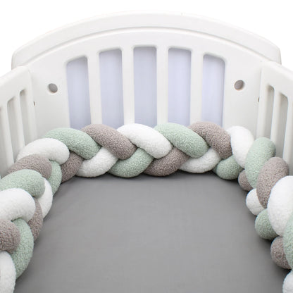 contour de lit tressé 3 brins vert sauge 3 couleurs installé autour des barreaux d'un lit bébé