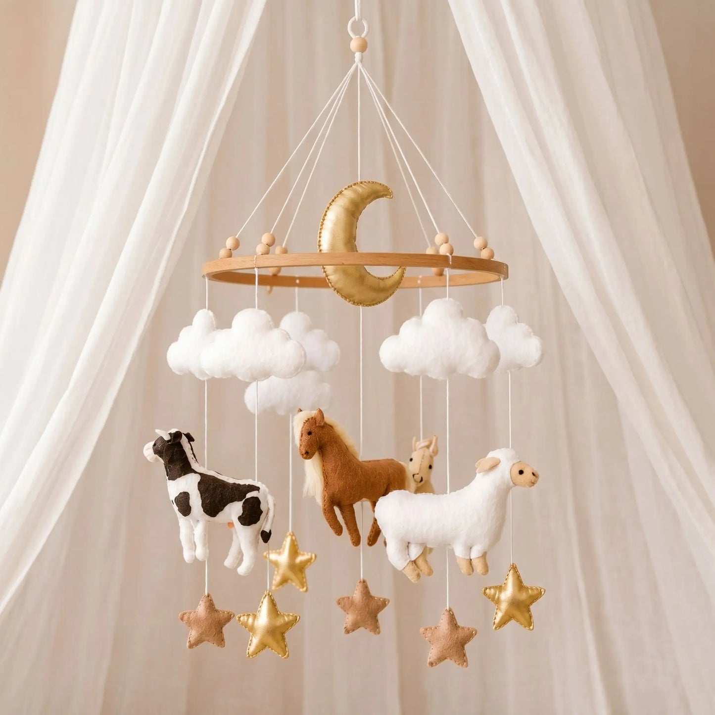 Mobile bébé artisanal sur le thème de la ferme suspendu avec une lune dorée centrale, des nuages blancs, des étoiles et des figurines en feutrine de vache, cheval et mouton