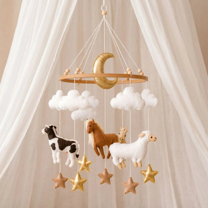 Mobile bébé artisanal sur le thème de la ferme suspendu avec une lune dorée centrale, des nuages blancs, des étoiles et des figurines en feutrine de vache, cheval et mouton
