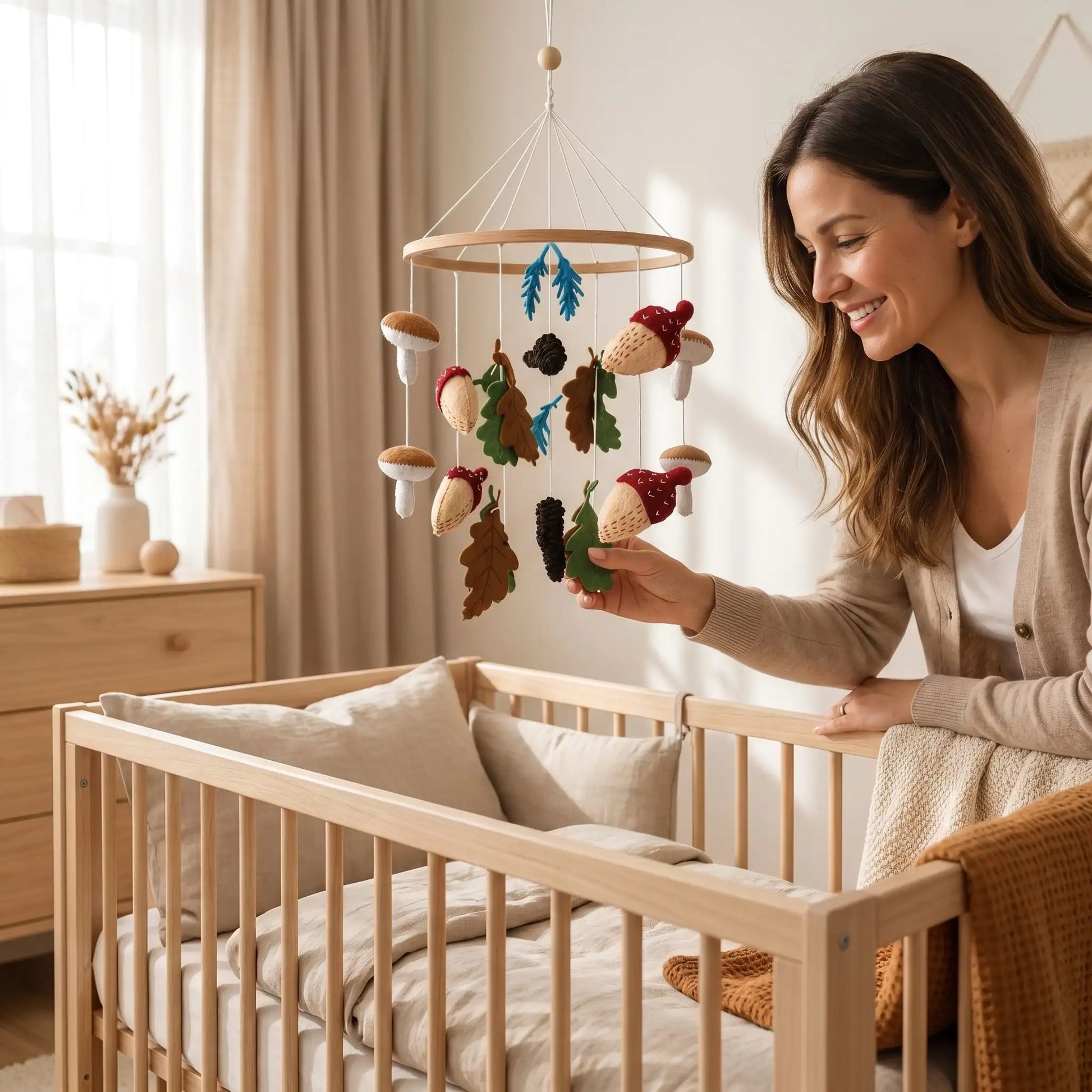 Mobile bébé d'automne artisanal en feutrine et bois suspendu au-dessus d'un lit comprenant des figurines de champignons, de glands brodés et de feuilles de chêne.