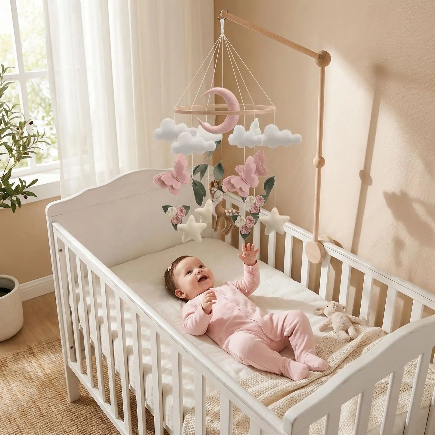 bébé dans un lit qui regarde en souriant son mobile bébé avec support bambi et papillon
