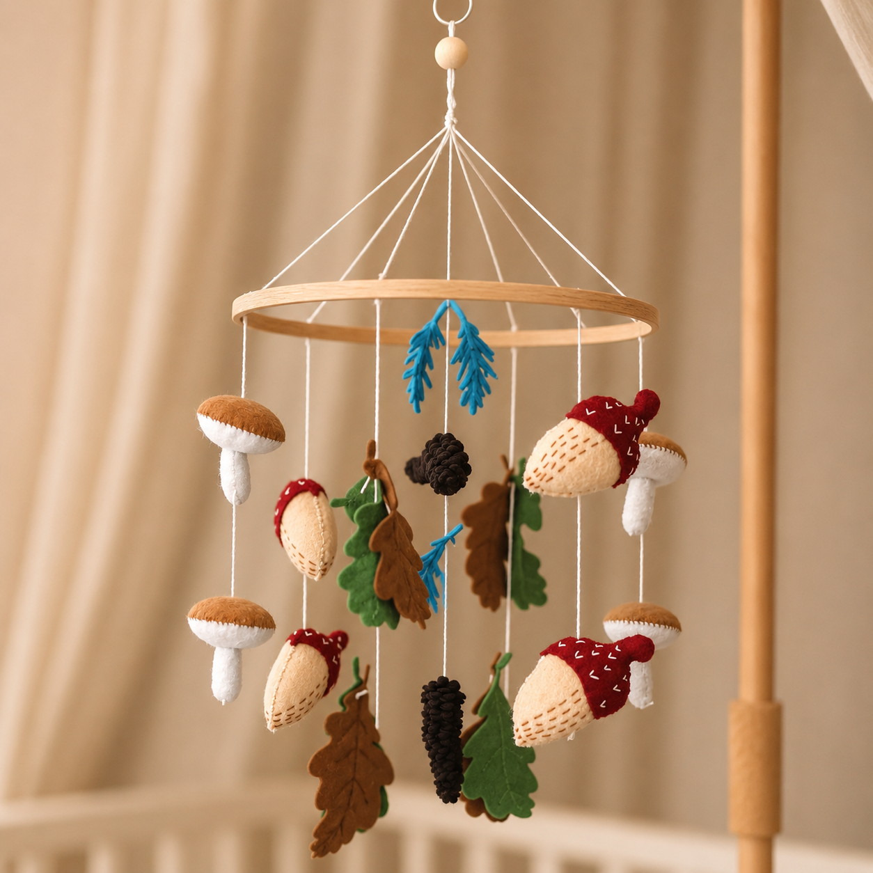 Mobile bébé d'automne en feutrine et bois suspendu au-dessus d'un lit avec flèche de lit et ciel de lit beige, comprenant des figurines de champignons, de glands brodés et de feuilles de chêne.