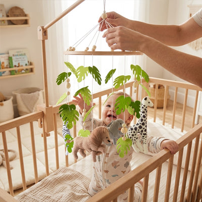 maman qui fixe un mobile bébé savane en feutre et bois artisanal