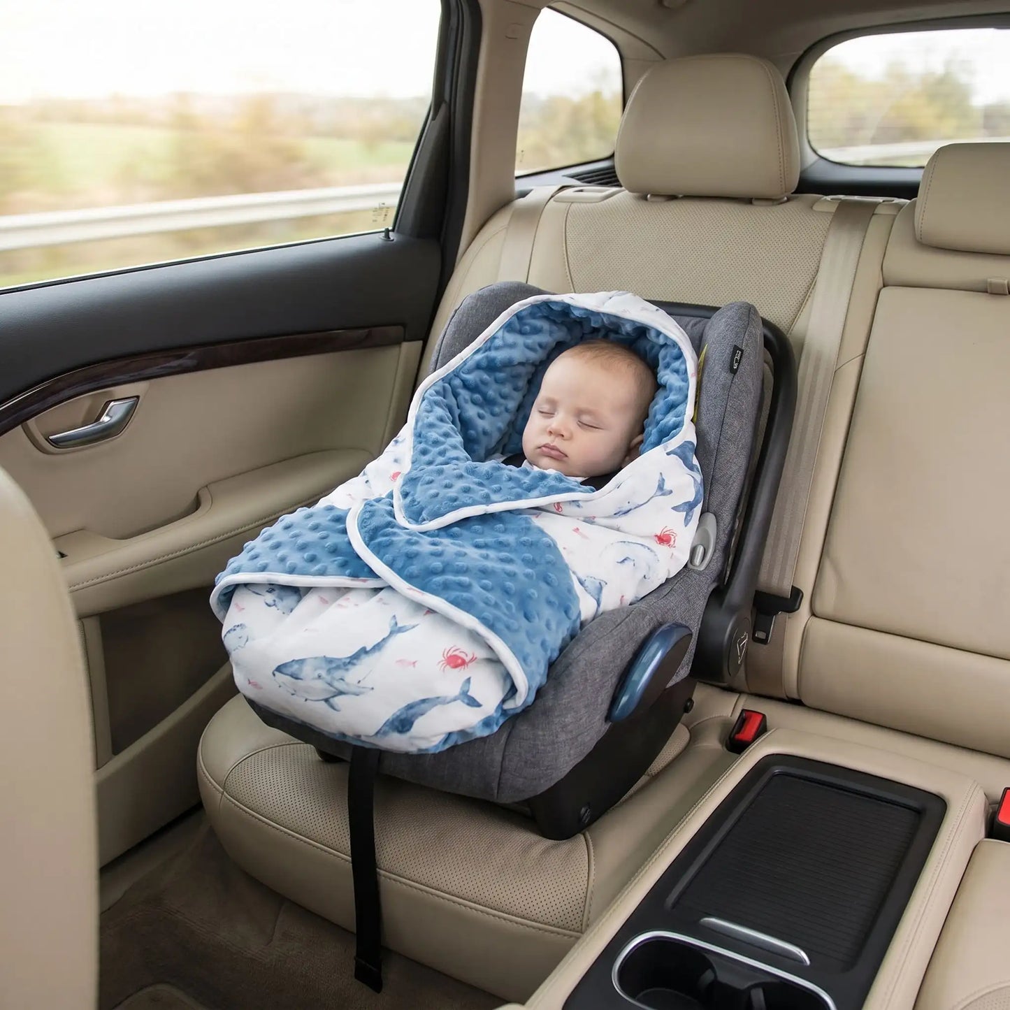 bébé qui dort dans une voiture dans son siège auto avec son nid d'ange cosy chaud bleu pour l'hiver