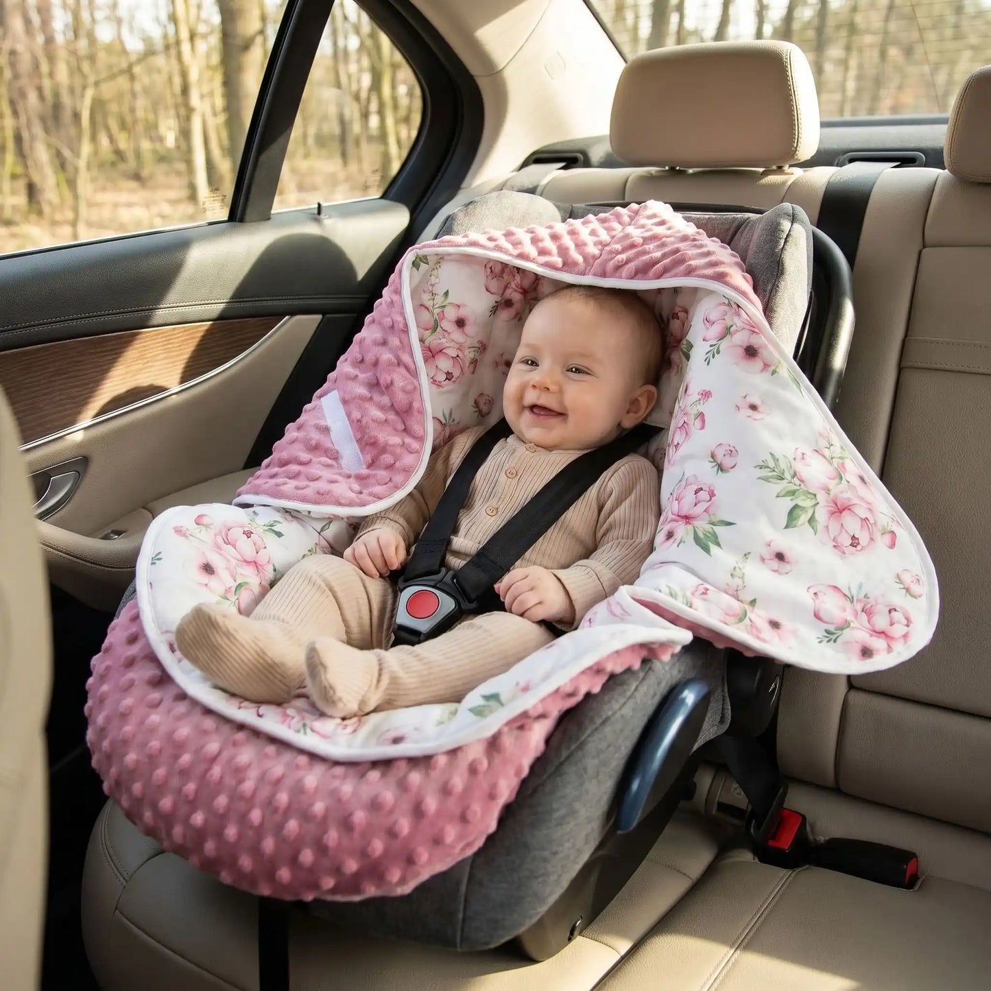 bébé en barboteuse dans un siège auto avec un nid d'ange poussette et cosy pour fille avec des fleurs ouvert qui l'enveloppe