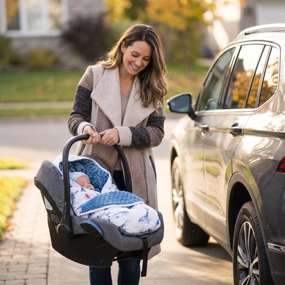 maman qui porte son bébé dans son siège auto  enveloppé dans son nid d'ange cosy bleu garcon baleines 