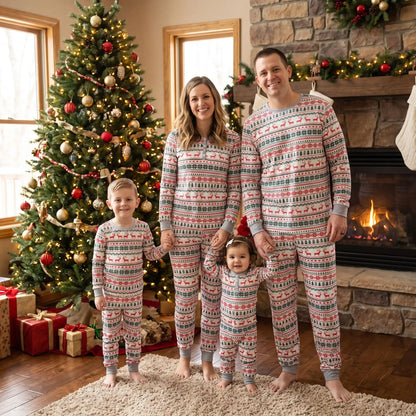 une famille au complet devant une cheminée et un sapin de noel habillée avec le même pyjama assorti pour toute la famille noel en blanc