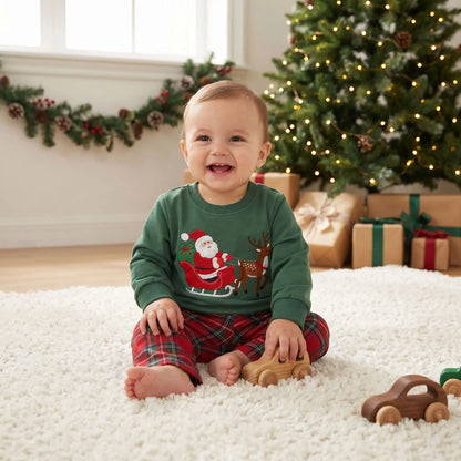 bébé qui sourit assis sur un tapis blanc moelleux avec un pyjama de noël pour bébé ensemble de deux pièces avec un motif de père noël et un renne 