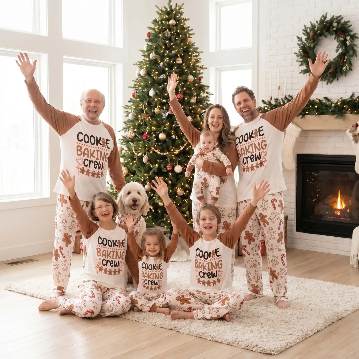 une famille et les grands-parents tous habillés avec le même pyjama noël famille petits biscuits de noël qui lèvent les bras et sourit devant le sapin