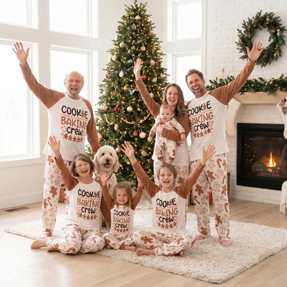une famille et les grands-parents tous habillés avec le même pyjama noël famille petits biscuits de noël qui lèvent les bras et sourit devant le sapin