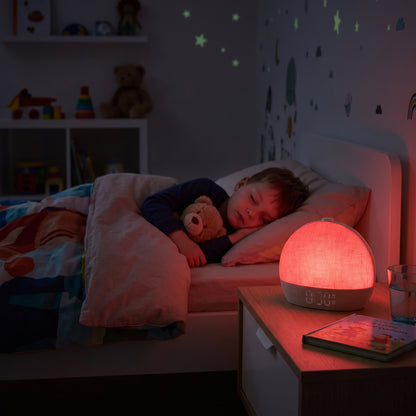 enfant qui dort paisiblement dans son lit avec un réveil simulateur d'aube qui change de couleurs
