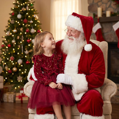 petite fille sur les genoux du père noel qui le regarde avec admiration habillée d'une robe de noel bébé fille en velours rouge