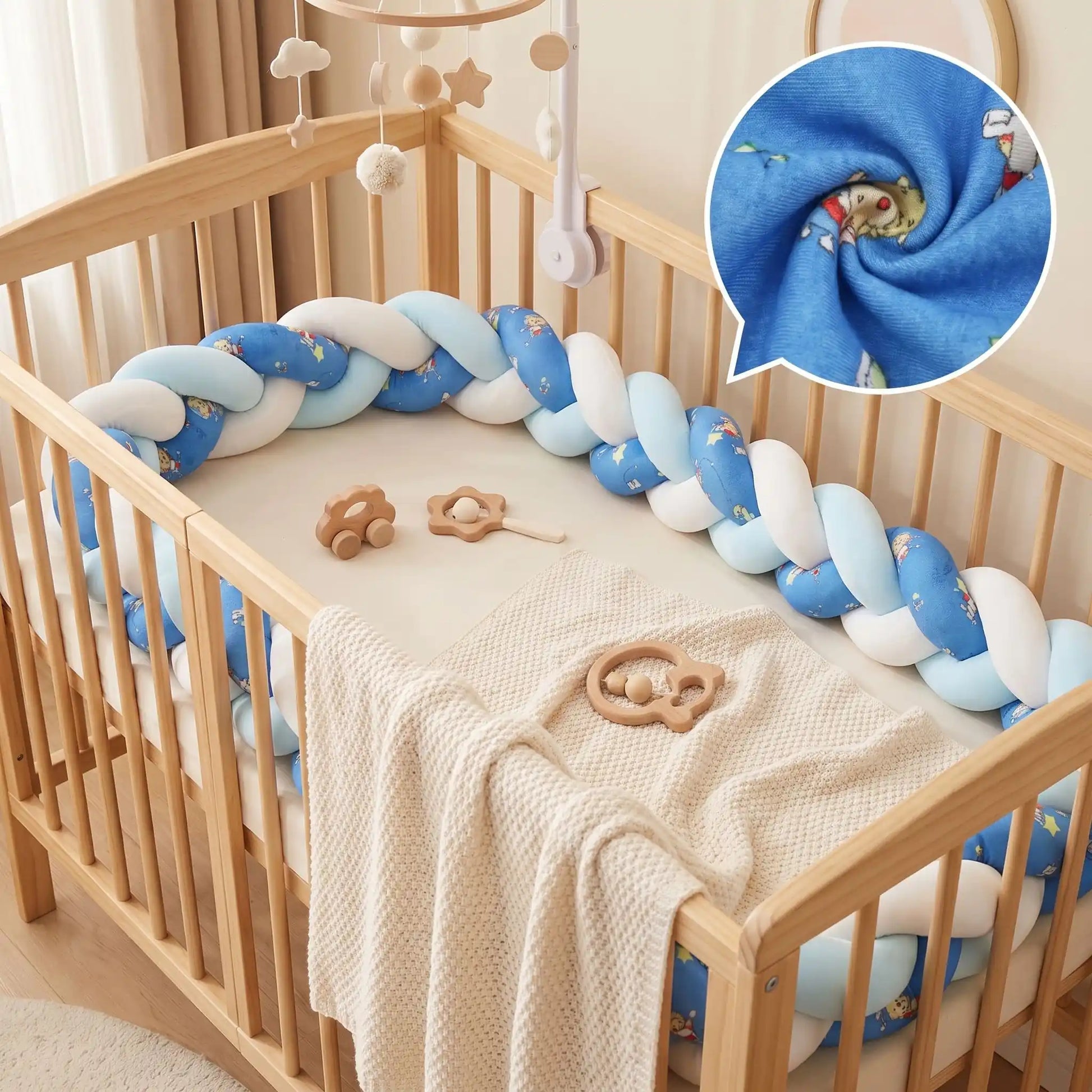 Tour de lit bébé tressé 3 brins dégradé de bleu et blanc avec motifs enfantins, installé dans un berceau