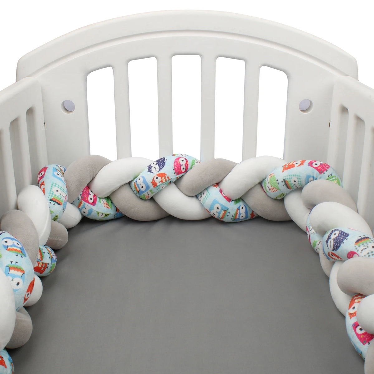 Tour de lit bébé tressé 3 brins gris, blanc et motifs chouettes bleues dans un berceau