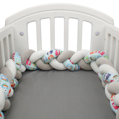 Tour de lit bébé tressé 3 brins gris, blanc et motifs chouettes bleues dans un berceau
