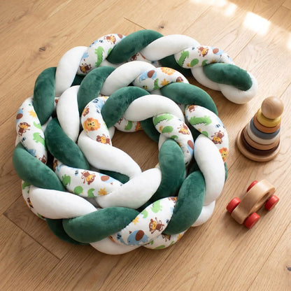 Tresse de lit bébé vert foncé et motifs animaux de la savane enroulée sur elle-même sur un plancher en bois