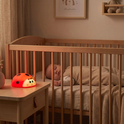 bébé qui dort paisiblement dans son lit avec une veilleuse bébé coccinelle à lumière rouge apaisante pour le sommeil