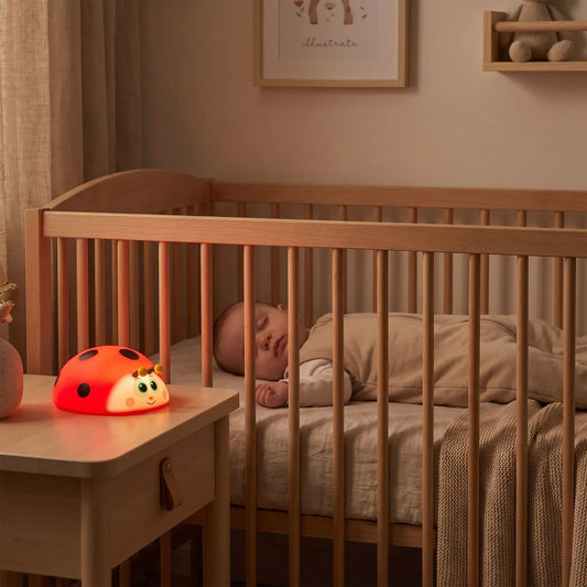 bébé qui dort paisiblement dans son lit avec une veilleuse bébé coccinelle à lumière rouge apaisante pour le sommeil